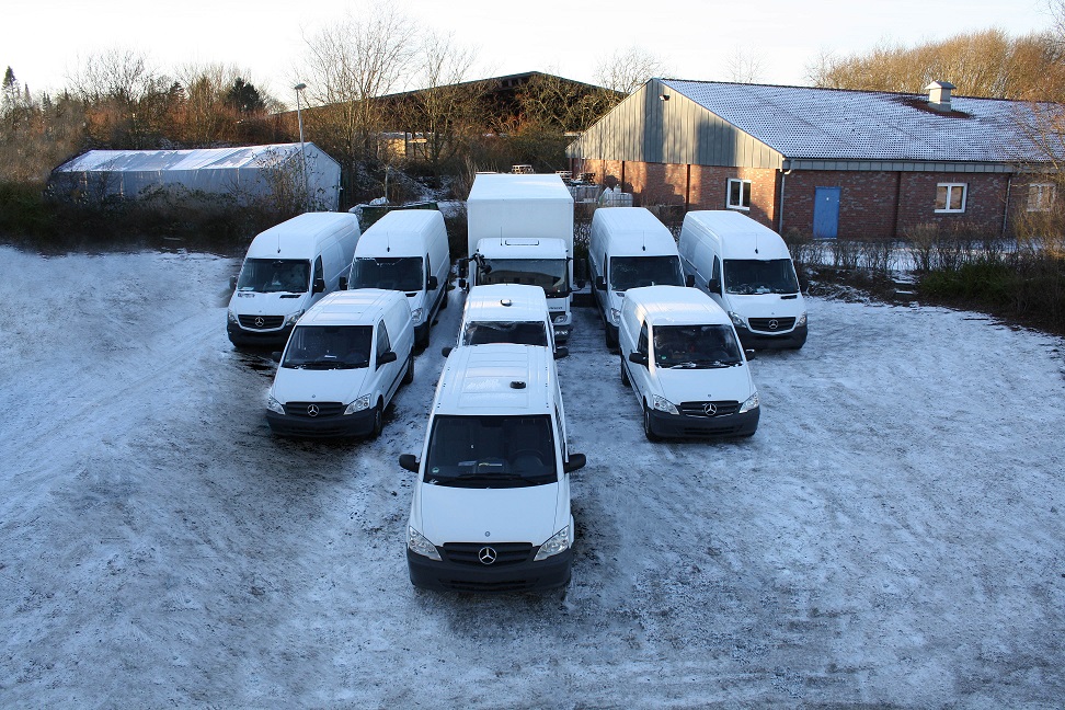 Weiße Transporter von m2solutions stehen nebeneinander auf einem schneebedeckten Parkplatz.